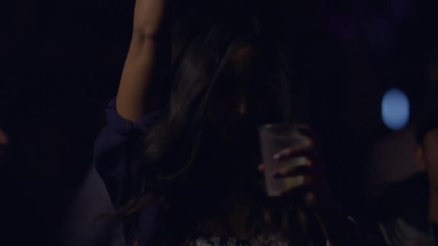 A woman dances with a drink in her hand
