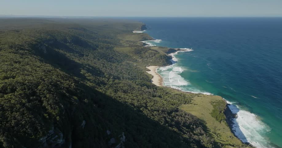 Aerial view of mountains covered with vegetation next to the coastline with crystalclear waters