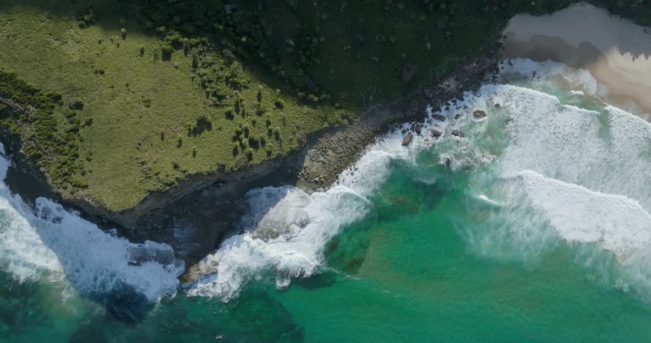 Clear water waves splash as they roll into shore along the coast