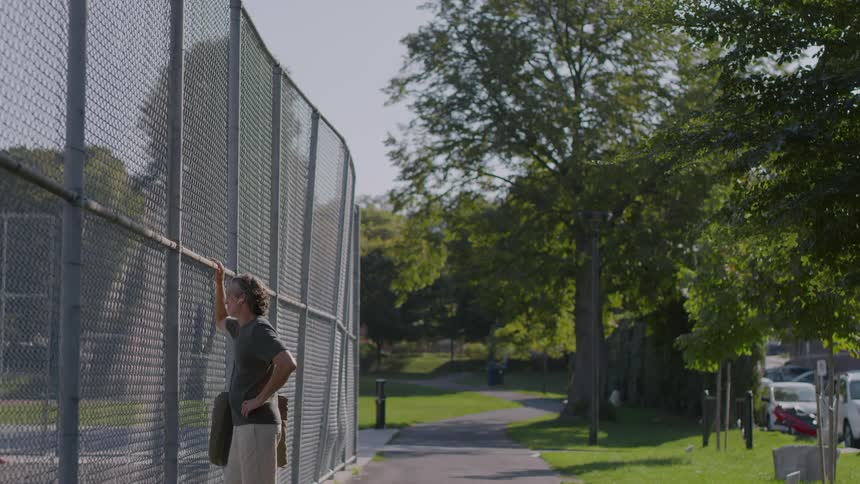 A man leaning his hand against a fence on a sports court