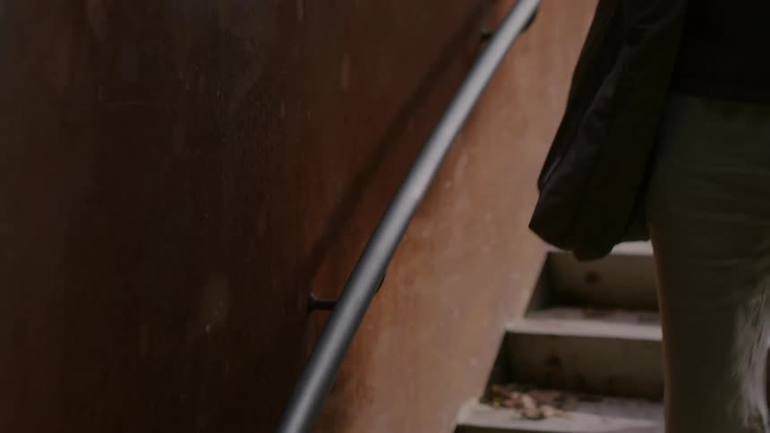 Person walking down an outdoor staircase with a steel railing