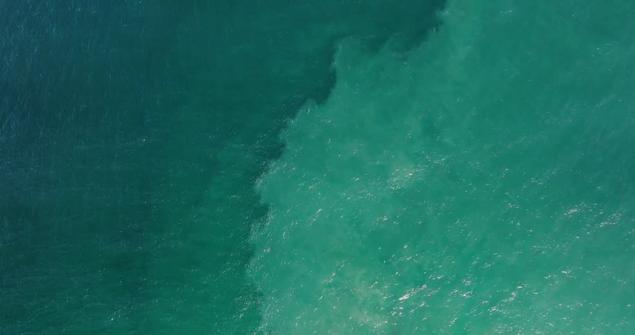 Topdown aerial of the shifting shades of blue in the ocean