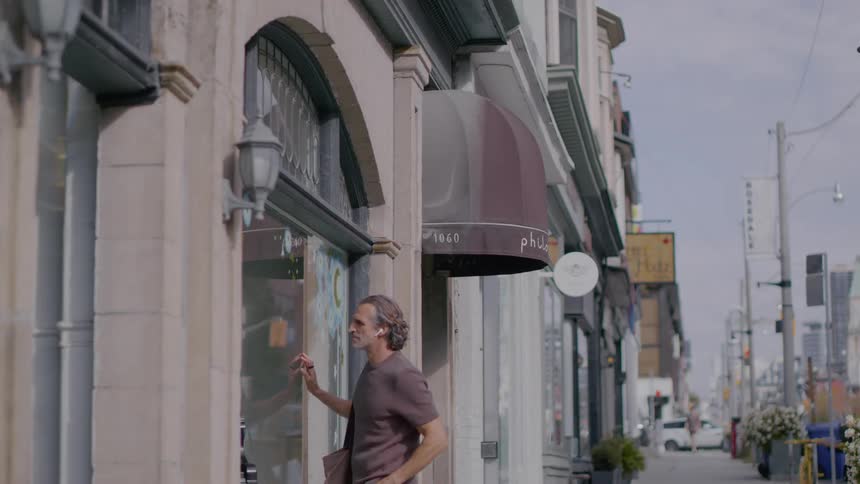 Man looks through the window before entering a street shop