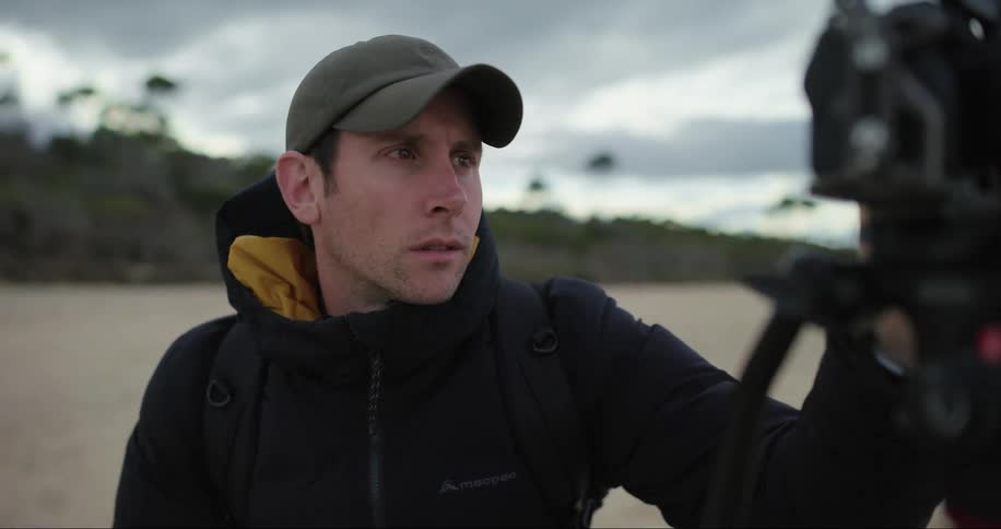 Photographer in an outdoor setting setting up a professional camera on a cloudy day