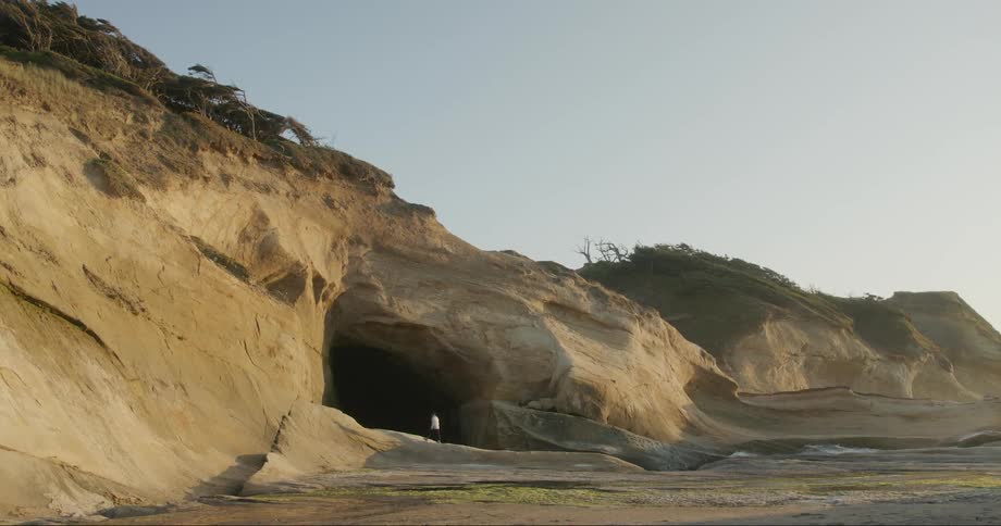 Person heading towards the seashore with a dark entrance hole