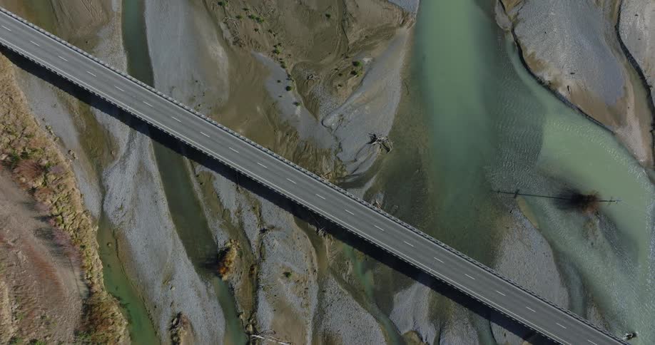 Drone view of a roadway bridge going over a river on a bright day