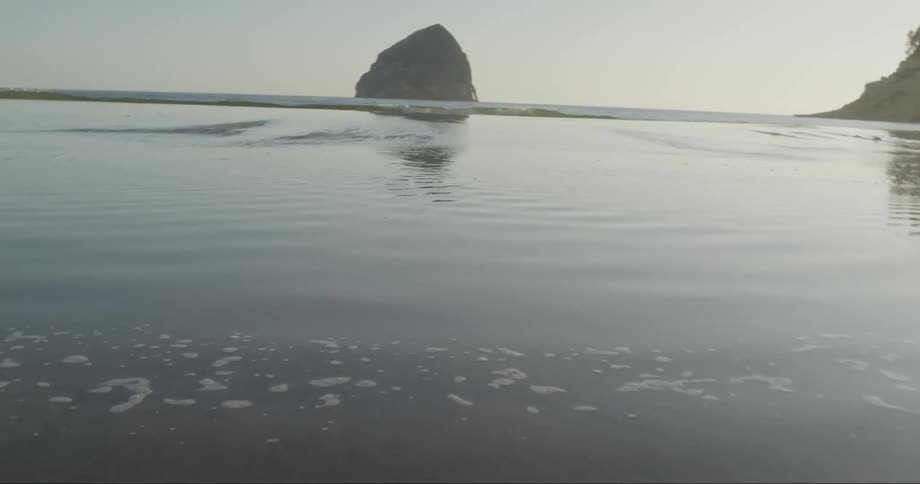 Water on the beach in twisted angle as the sun reflects off the water