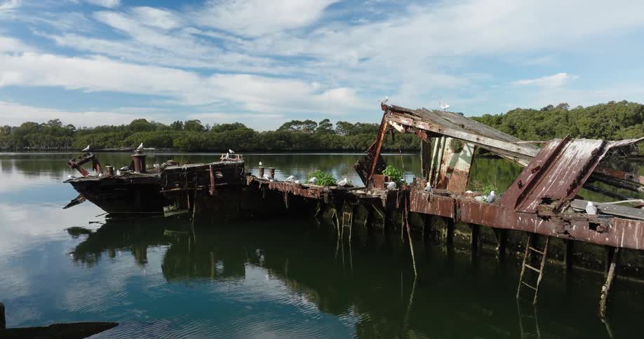 A ruined rusted structure on a lake full of birds overhead