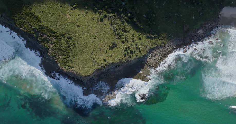 Aerial view of the sea crashing with waves on the coastline and beach sand