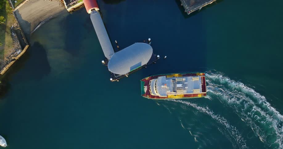 A boat approaching a pier to dock and making waves in the water