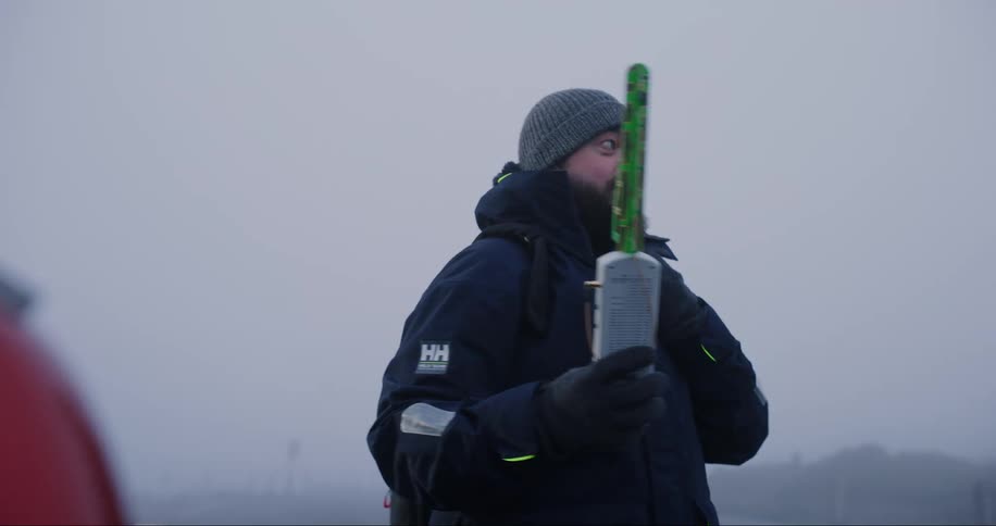 Man using a laptop holds an antenna on a cold morning in the mountains