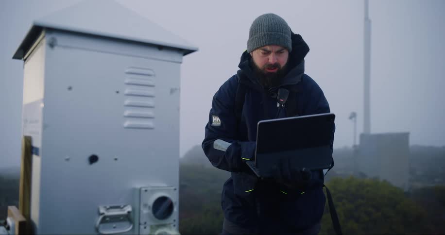 Worker holding a laptop and setting up a small outdoor platform