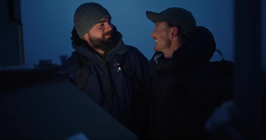 Two men in warm clothing talking and laughing as they work