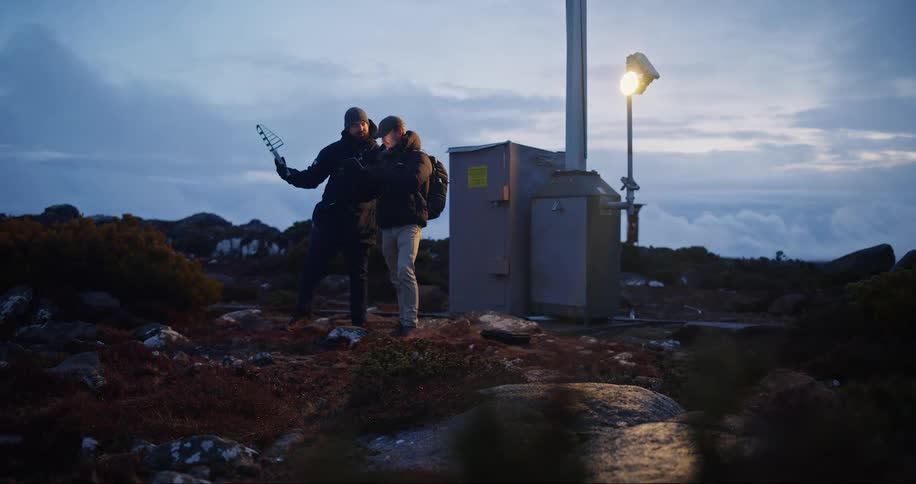 Two men in jackets talking and with work equipment in their hands