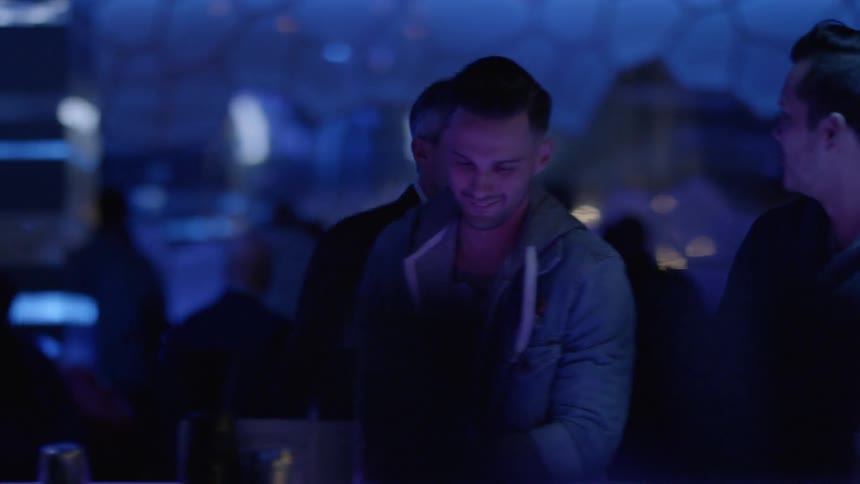 A man walks up and greets friends in a club