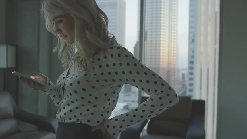 Woman using her smartphone while wearing a polka dot blouse