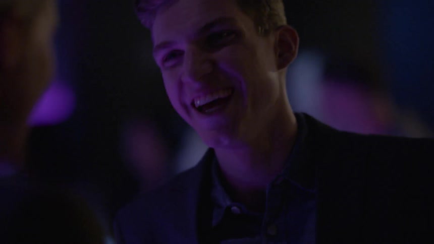 Two well-dressed men talking and laughing in a club