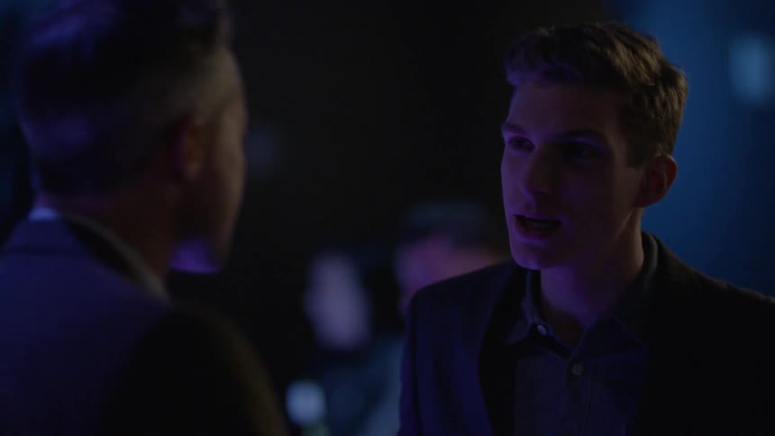 Two well-dressed men talking and laughing in a club