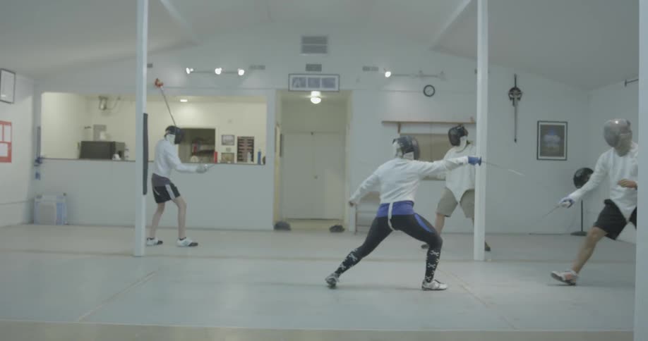 Four people practice fencing in a small area