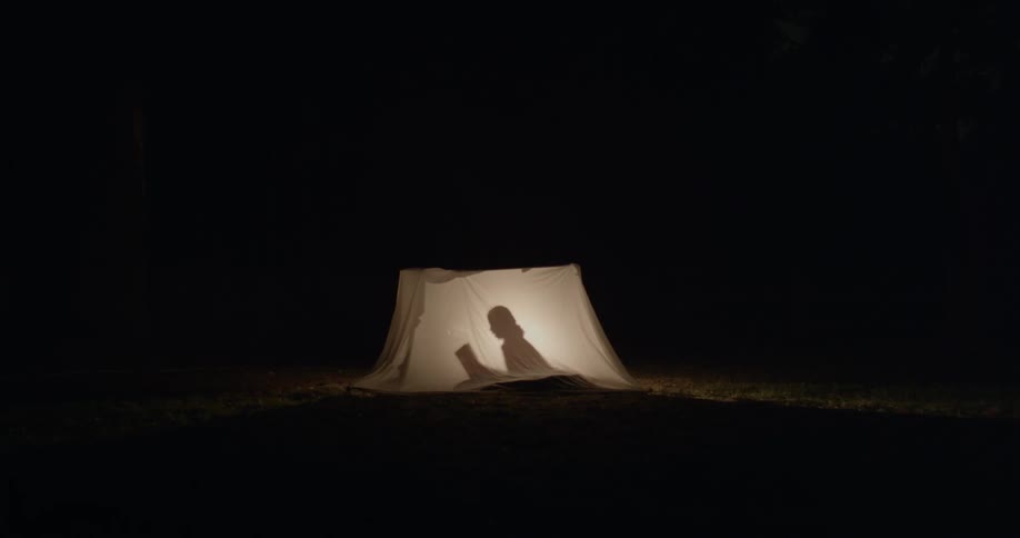 Silhouette of a person in a tent at night