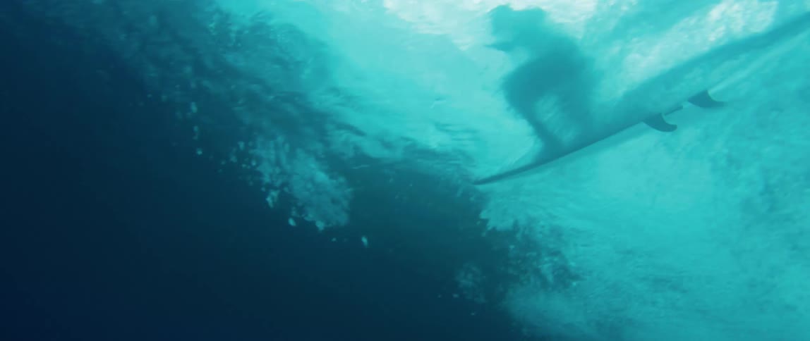 View from inside the sea of a person surfing a wave