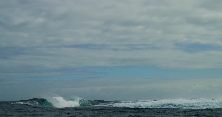 Distant view of big wave breaking on shallow reef