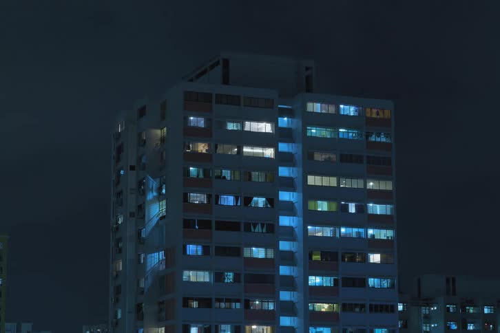 Apartment with lights turning on during the cloudy night in the city