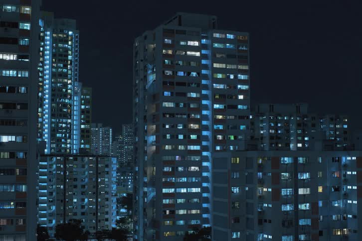 View of urban buildings with interior residential lights turning on in a nighttime time lapse