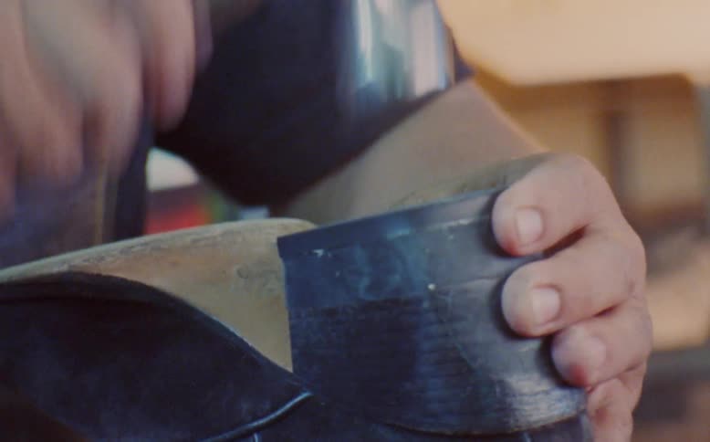 Man performing manufacturing work hammering a nail into a leather shoe