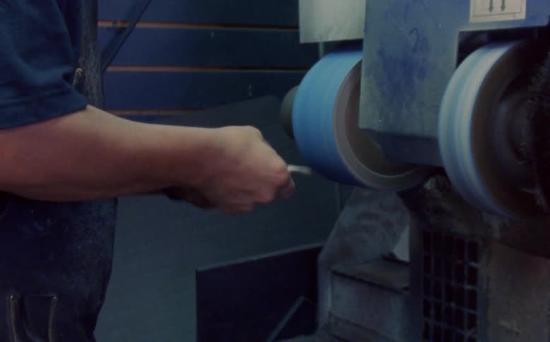 A shoemaker smoothing a leather sole on a machine
