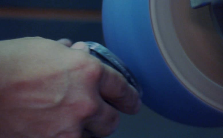 A man uses a wheeled power tool to smooth the surface of another object