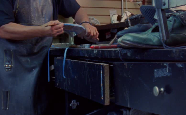 Man performing the painting of a womens shoe in a manufacturing job