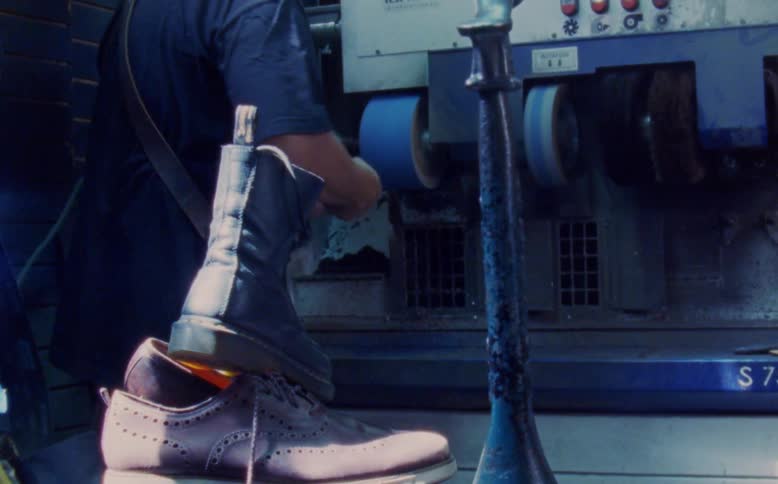 Shoemaker polishes shoes on a machine in his workshop