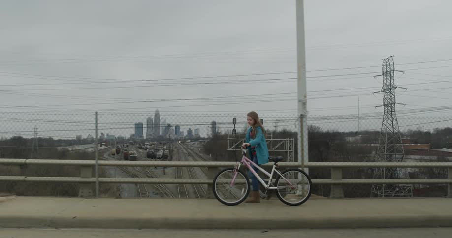 Girl walks her bike over a bridge