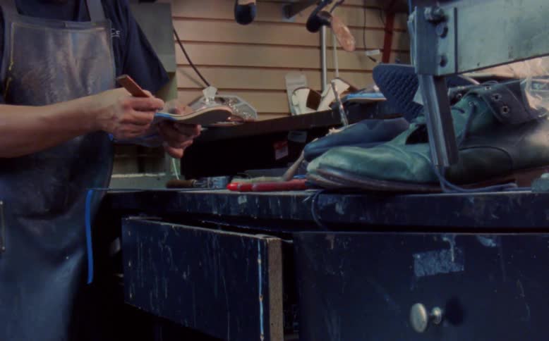 A working man putting a tape on a womans shoe