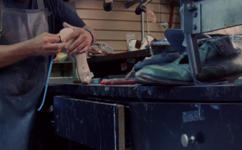 Hand of a man engaged in manufacturing on a womens highheeled shoe