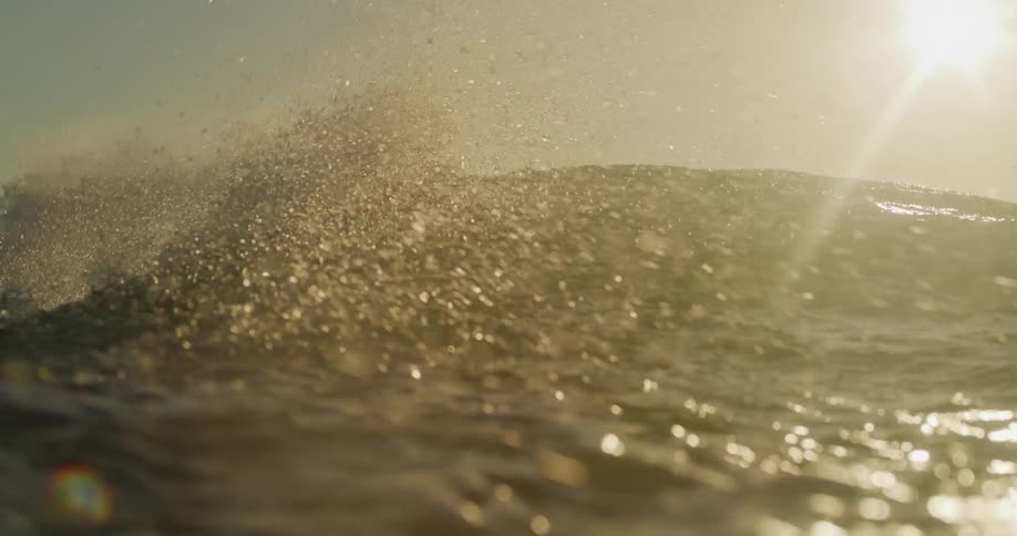 View from inside the sea with a moving wave and the sun