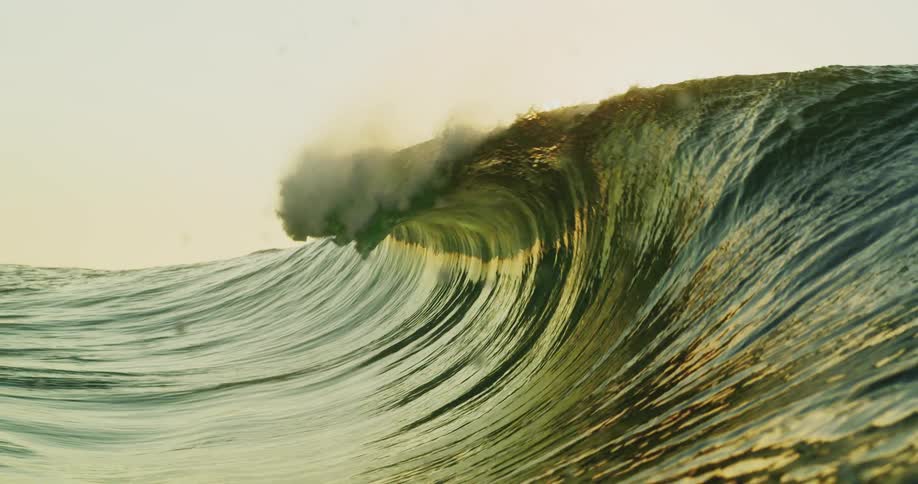 View of a wave in motion with crystalclear water and the sun in the background