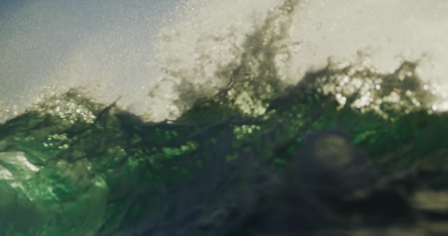 Green ocean waves break under morning sunlight