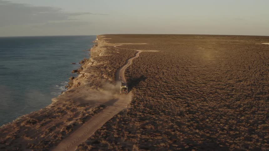 A vehicle drives by the cliff