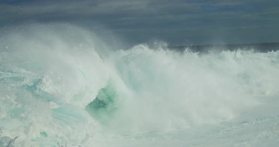 Ocean waves break and spray during the day