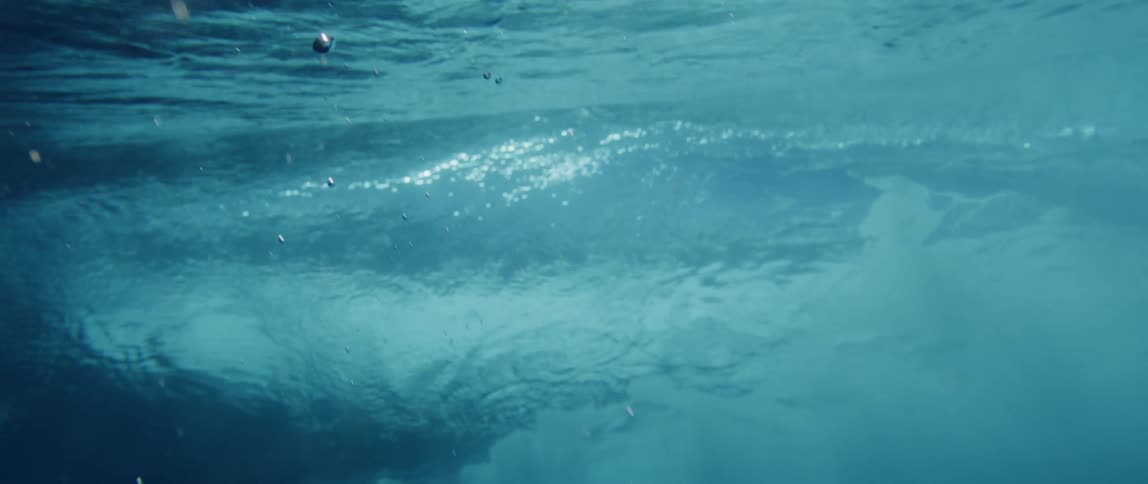 Sunlight reflects on the water as it ripples and bubbles float below the surface and darkness falls