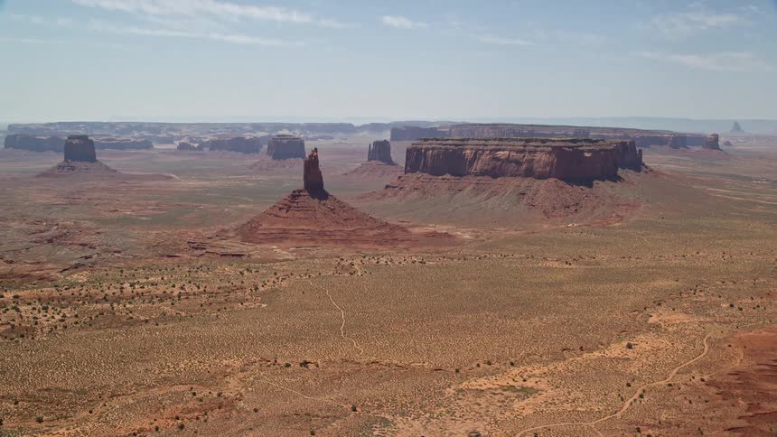 Aerial footage of Big Indian Butte and Sentinel Mesa as the camera flies away showcasing the stunning landscape of Monument Valley Utah and Arizona