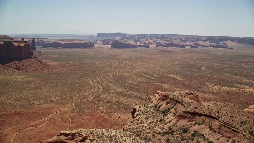 Aerial video footage captures the breathtaking landscape of Monument Valley as the camera flies over Mitchell Mesa towards distant buttes in the arid Utah-Arizona border region