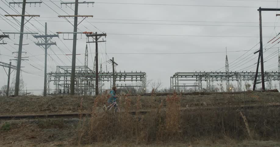 Child walks bike alongside railroad tracks