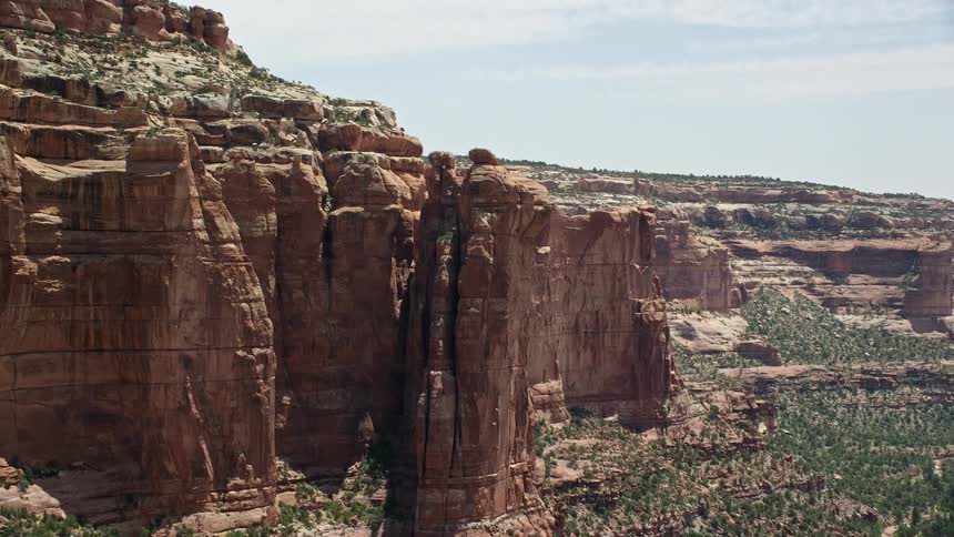 Discover the stunning beauty of Arch Canyon in Utah as you soar above breathtaking rock formations and boulders under the sunny southwestern sky