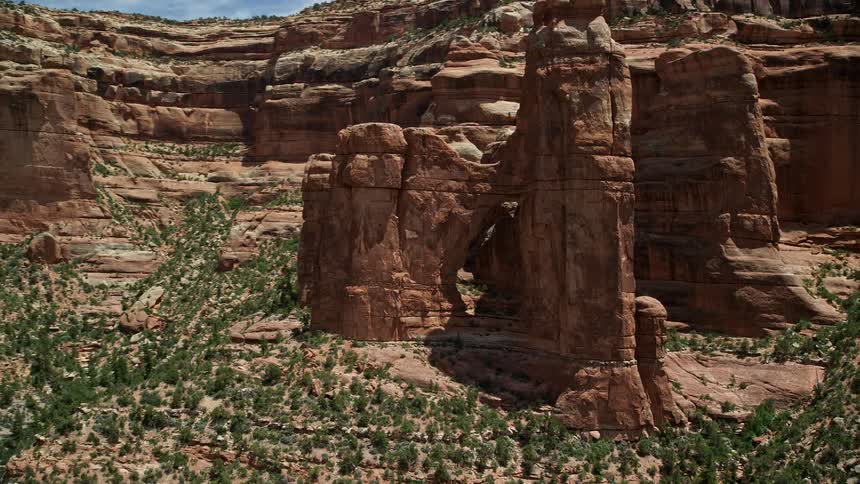 Aerial footage showcases the stunning Angel Arch in Arch Canyon Utah as rocky formations bathed in sunshine orbit the area during daytime in the mesmerizing Southwest United States