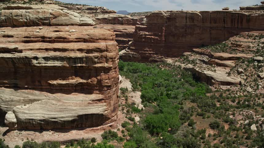 Low altitude aerial footage of a sunny day flying through the arid and scenic Grand Gulch canyon in the Grand Gulch Primitive Area Utah