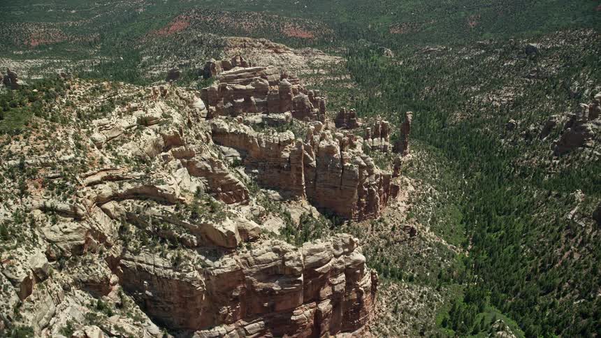 Aerial view of orbiting rock formations in a forested canyon at Manti-La Sal National Forest Utah during a sunny day