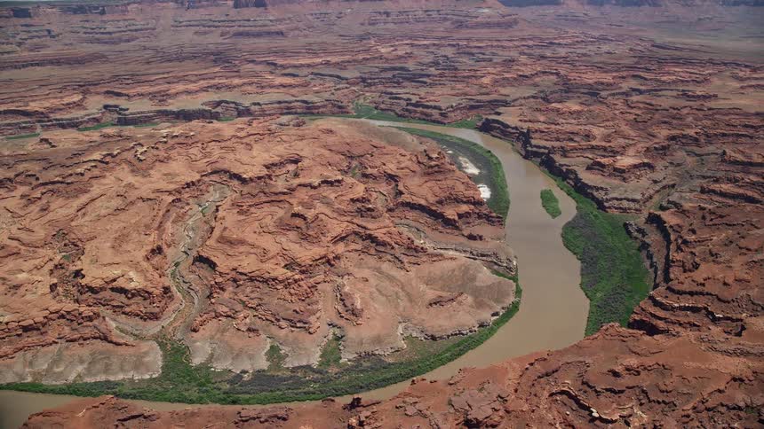 Aerial footage of the Colorado River flowing through Meander Canyon in Canyonlands National Park showcasing the arid desert landscape and stunning natural beauty of the Southwest United States